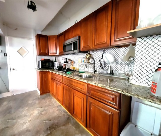 kitchen featuring light stone countertops, backsplash, stainless steel appliances, and sink