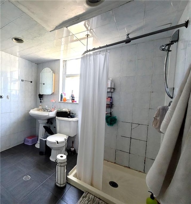 bathroom featuring a shower with shower curtain, toilet, tile walls, and tile patterned floors