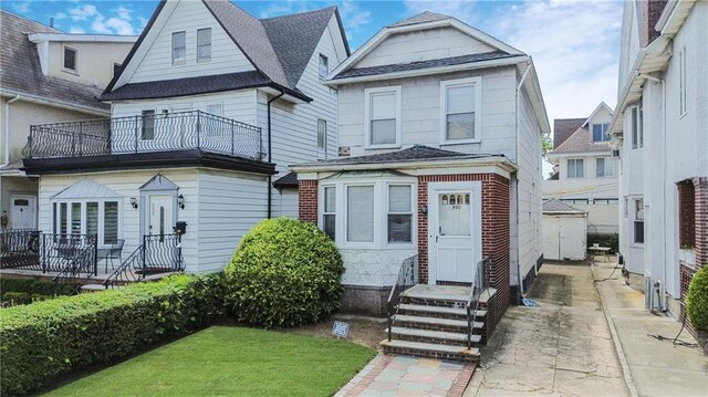 view of front facade featuring a front yard and a balcony