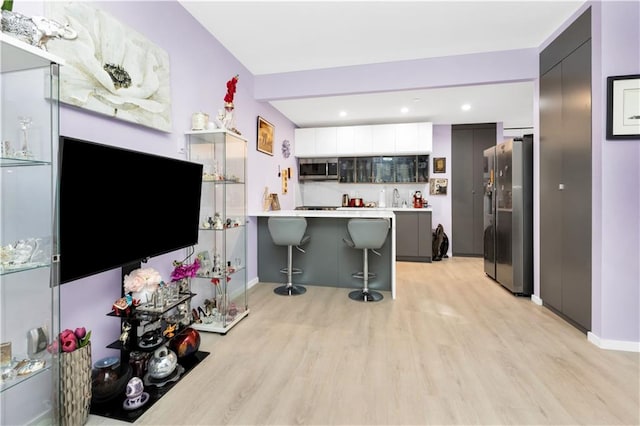 kitchen featuring kitchen peninsula, a breakfast bar, light hardwood / wood-style floors, and appliances with stainless steel finishes