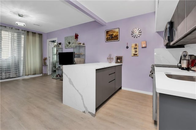 kitchen with gray cabinetry, light wood-type flooring, and beamed ceiling