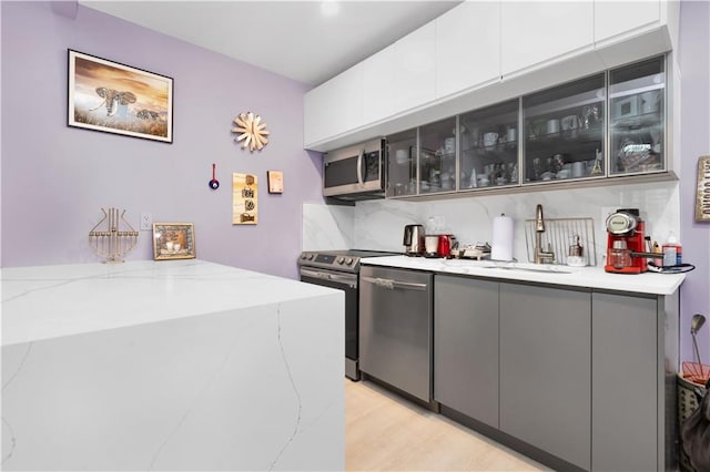 bar featuring tasteful backsplash, light stone countertops, sink, and stainless steel appliances