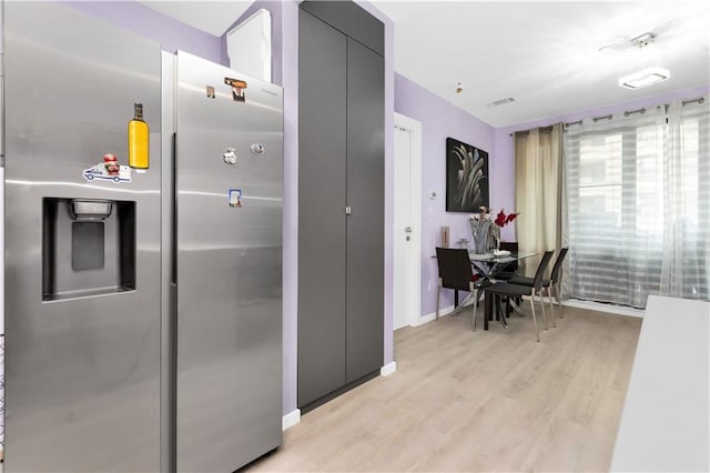 kitchen with stainless steel refrigerator with ice dispenser and light hardwood / wood-style flooring