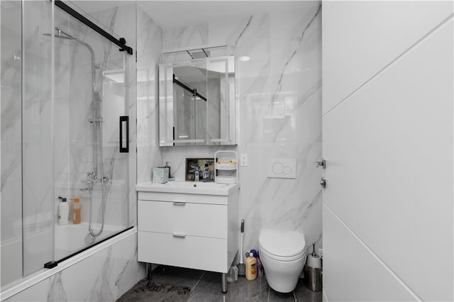 full bathroom with vanity, toilet, tile walls, and bath / shower combo with glass door