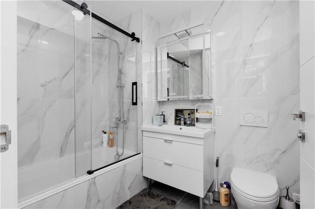 full bathroom featuring shower / bath combination with glass door, vanity, toilet, and tile walls