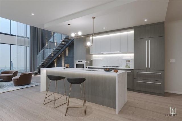 kitchen with pendant lighting, gray cabinets, an island with sink, and stainless steel appliances