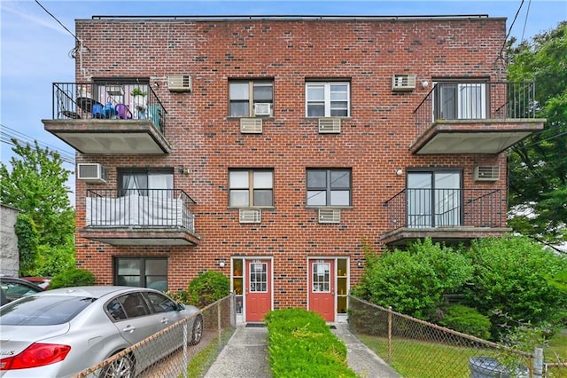 1021 E 87th St Unit 6B, Kings, NY 11236 - view of front of house featuring a balcony, brick siding, a wall mounted AC, fence, and cooling unit