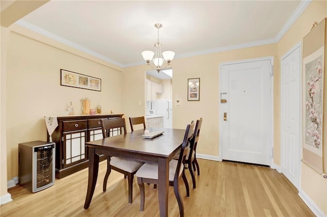 dining space featuring baseboards, beverage cooler, a chandelier, ornamental molding, and light wood-style flooring