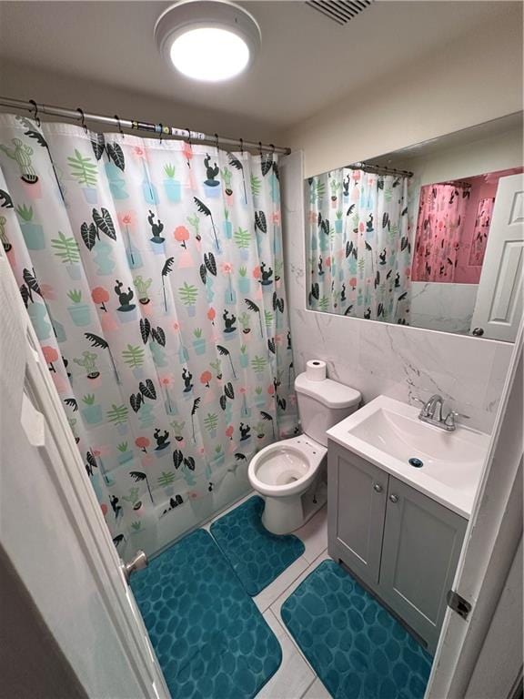 full bathroom featuring shower / bath combo, vanity, tile patterned floors, toilet, and tile walls