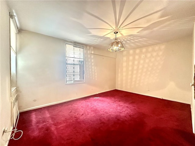 carpeted empty room featuring a chandelier and baseboards