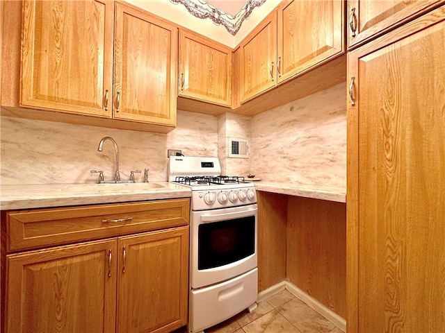 kitchen with light tile patterned floors, white range with gas cooktop, light countertops, and backsplash