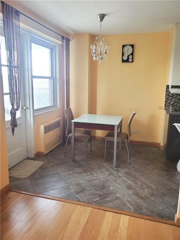 dining area featuring radiator heating unit, dark hardwood / wood-style floors, and a chandelier