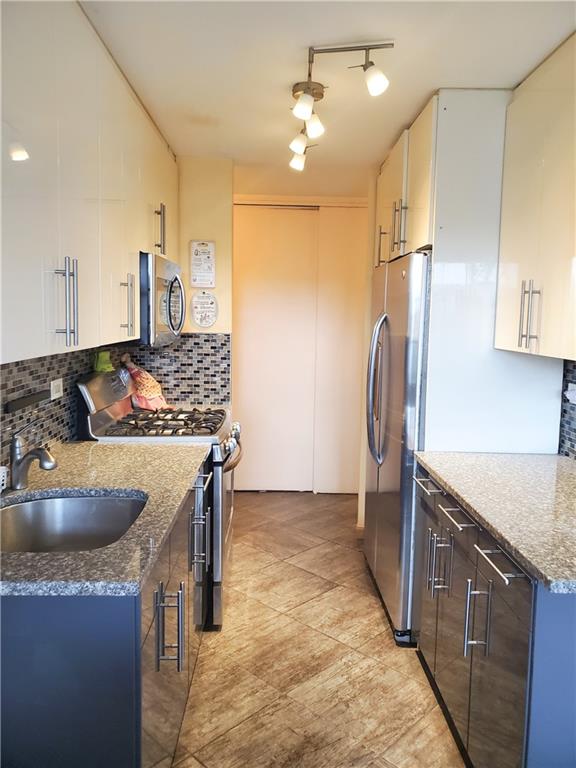 kitchen featuring stone counters, appliances with stainless steel finishes, sink, and white cabinets