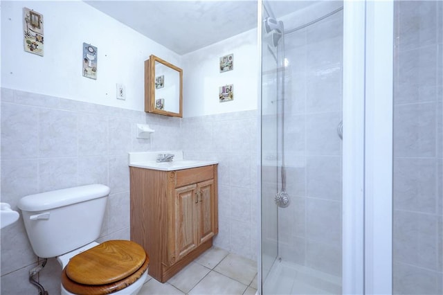 bathroom featuring tile patterned flooring, toilet, vanity, tile walls, and a shower stall