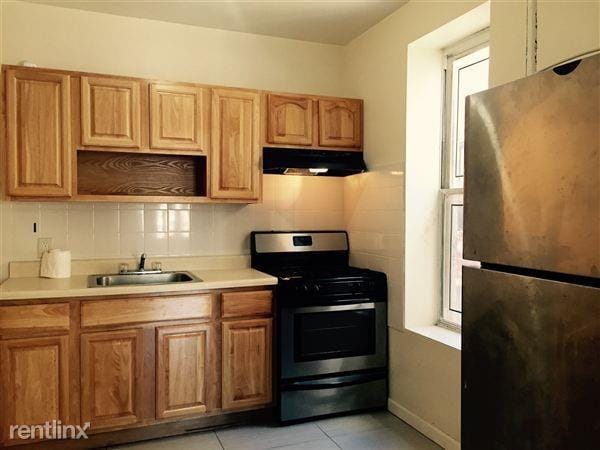 kitchen featuring a sink, ventilation hood, appliances with stainless steel finishes, and light countertops
