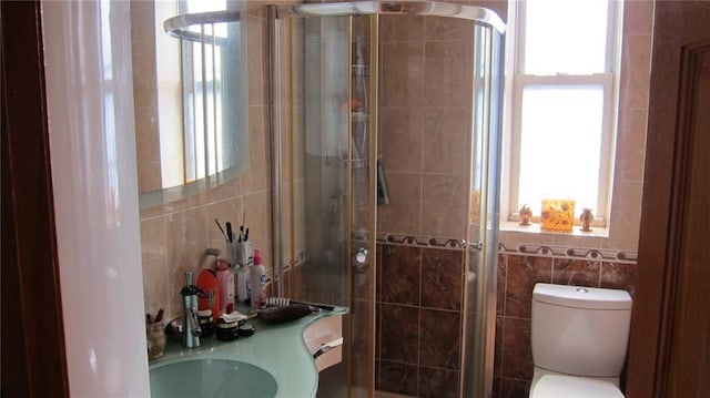 bathroom with a stall shower, plenty of natural light, and tile walls