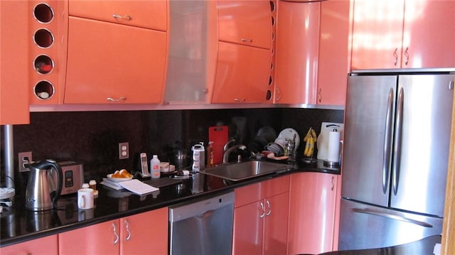 kitchen featuring dark stone counters, appliances with stainless steel finishes, a sink, and decorative backsplash