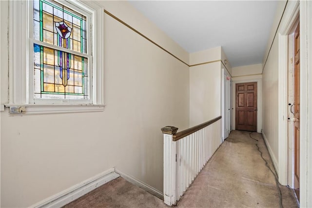 hall featuring baseboards, light carpet, and an upstairs landing