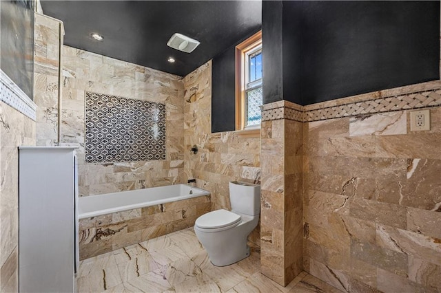 full bath featuring visible vents, toilet, marble finish floor, tiled tub, and tile walls