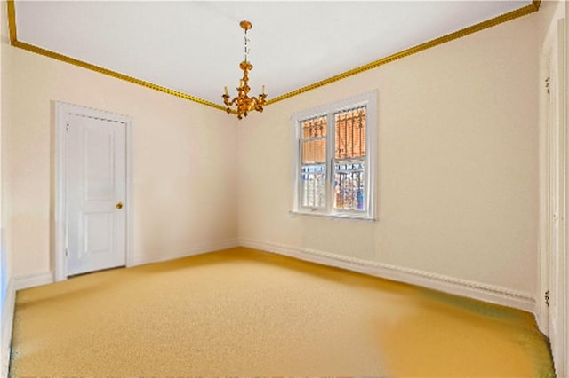 carpeted empty room featuring a chandelier, baseboards, and crown molding