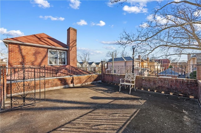 view of property exterior featuring a residential view, brick siding, fence, and a chimney