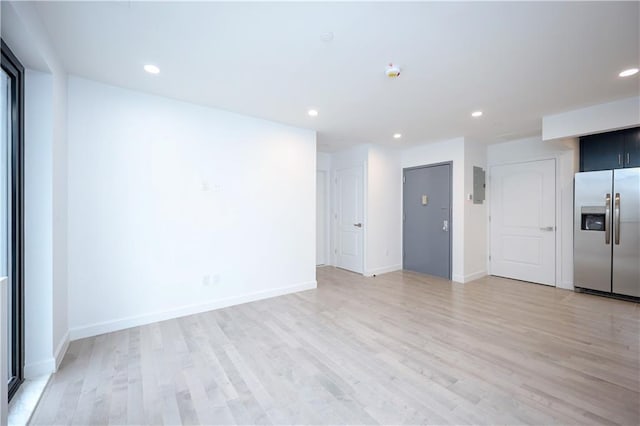 empty room with light hardwood / wood-style floors and electric panel