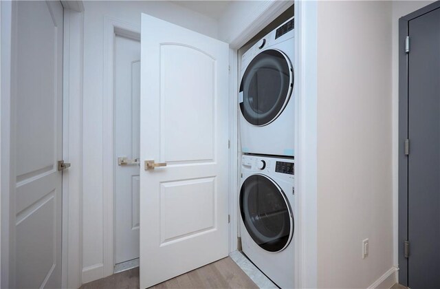 clothes washing area featuring stacked washer / drying machine and light hardwood / wood-style flooring