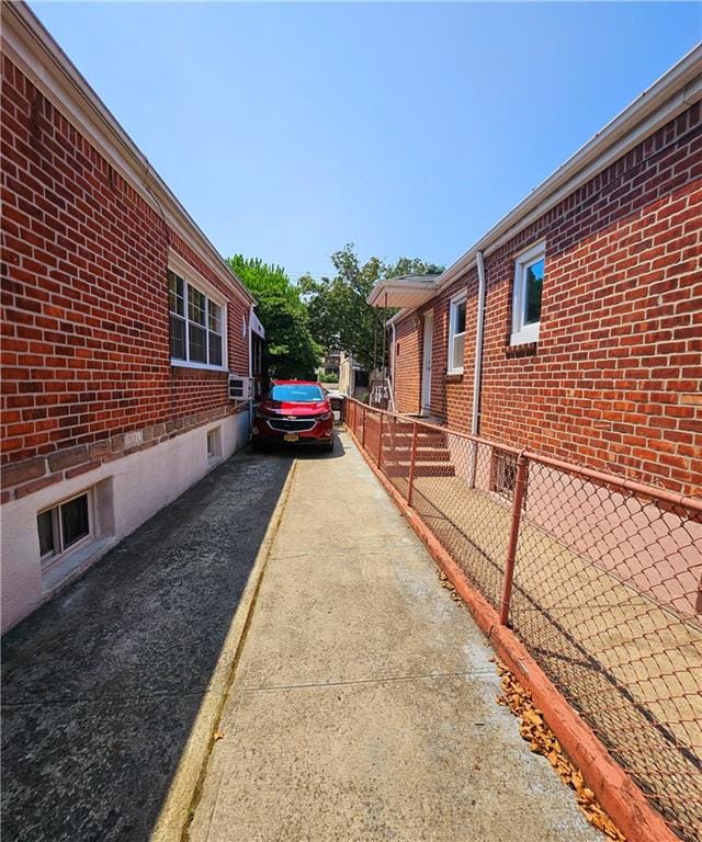 view of side of property with driveway, brick siding, and fence