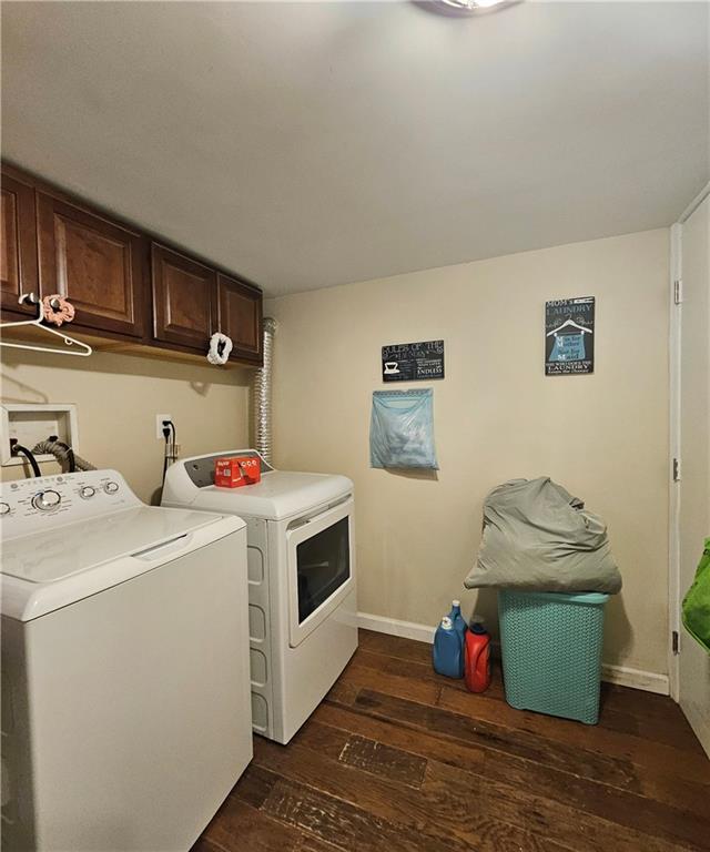 washroom with cabinet space, baseboards, dark wood-style flooring, and washing machine and clothes dryer