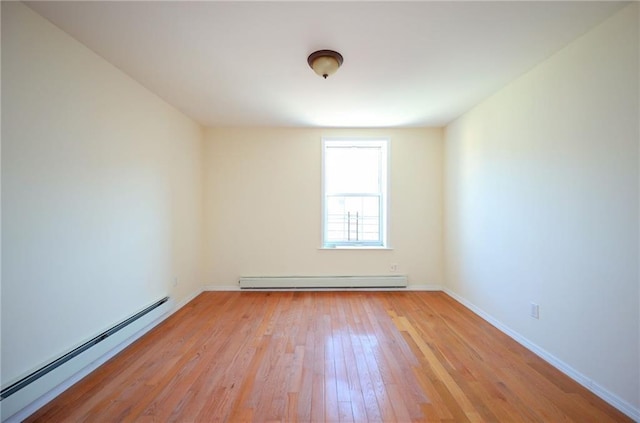 spare room featuring light wood-type flooring and baseboard heating