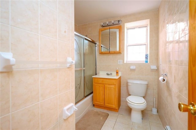 full bathroom with tile patterned floors, bath / shower combo with glass door, vanity, tile walls, and toilet