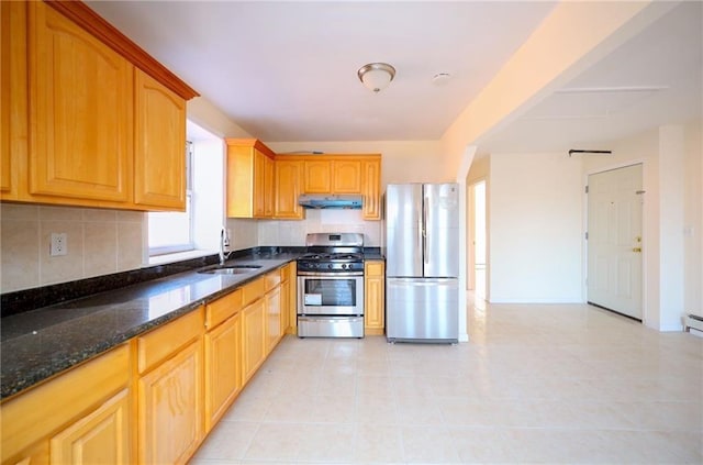 kitchen featuring tasteful backsplash, dark stone counters, stainless steel appliances, sink, and light tile patterned floors