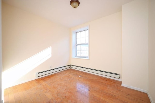 spare room featuring baseboard heating and hardwood / wood-style floors