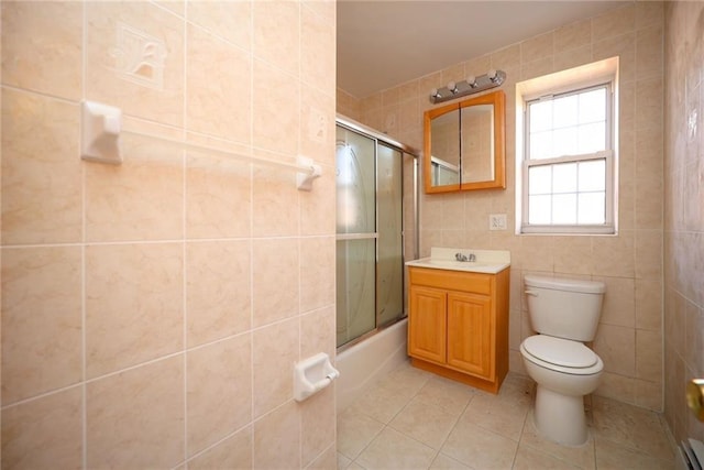 full bathroom with tile patterned flooring, enclosed tub / shower combo, toilet, vanity, and tile walls