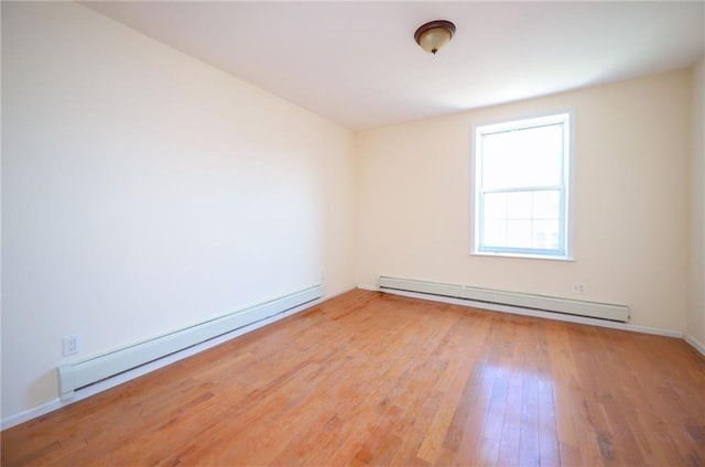 unfurnished room featuring hardwood / wood-style flooring and baseboard heating