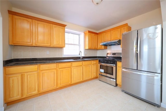 kitchen with backsplash, sink, dark stone counters, and appliances with stainless steel finishes