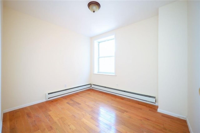 unfurnished room with baseboard heating and light hardwood / wood-style floors