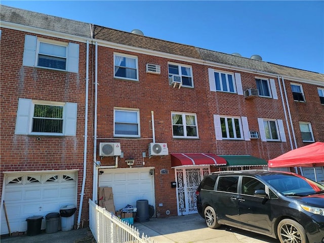 view of property featuring a wall unit AC, ac unit, cooling unit, and a garage