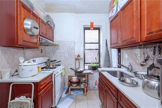 kitchen featuring backsplash, white gas range, sink, and light tile patterned floors