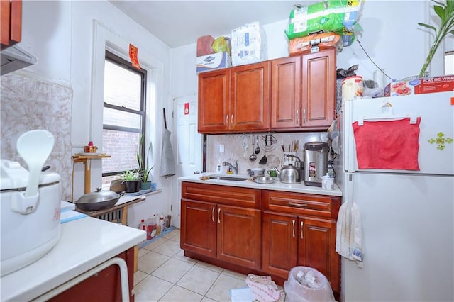 kitchen featuring backsplash, sink, light tile patterned floors, and white refrigerator