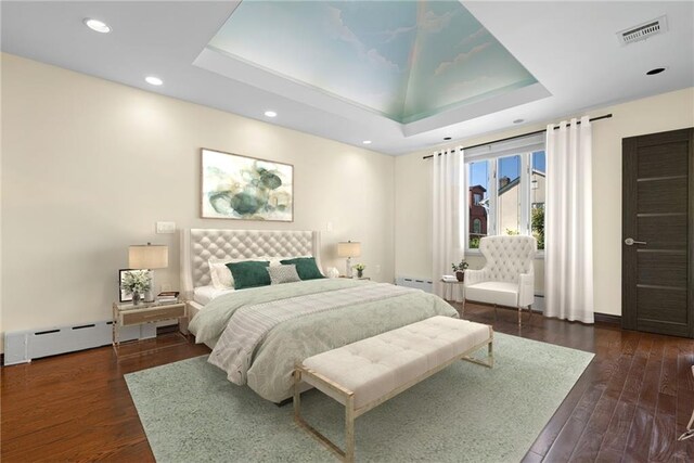 bedroom with baseboard heating, dark hardwood / wood-style flooring, and a tray ceiling