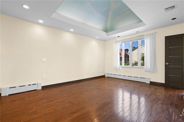 unfurnished room featuring a baseboard radiator, dark hardwood / wood-style flooring, and a raised ceiling