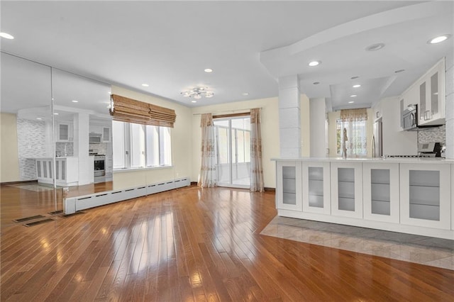 unfurnished living room featuring a baseboard radiator and hardwood / wood-style floors