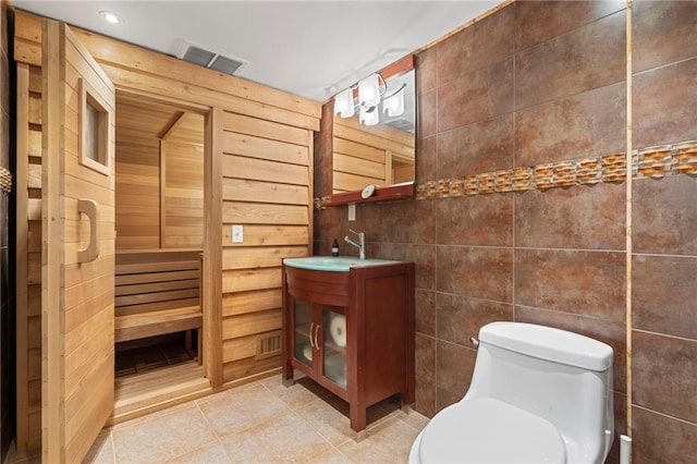 bathroom with toilet, tile walls, vanity, visible vents, and tile patterned floors