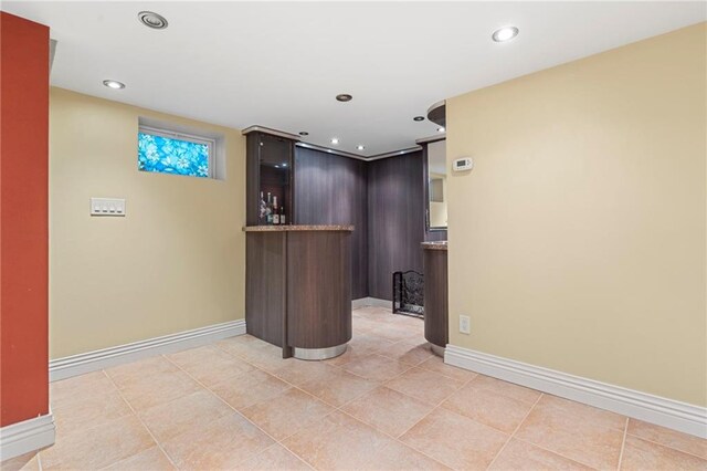 bar with dark brown cabinets and light tile patterned floors