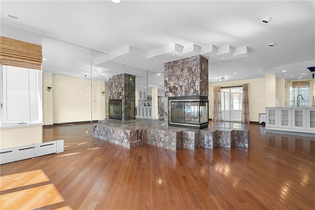 unfurnished living room with wood-type flooring, baseboards, a fireplace, and a sink