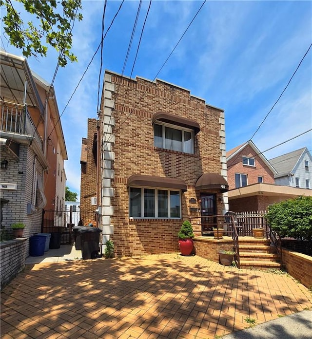 view of front of home featuring a patio area, fence, and brick siding