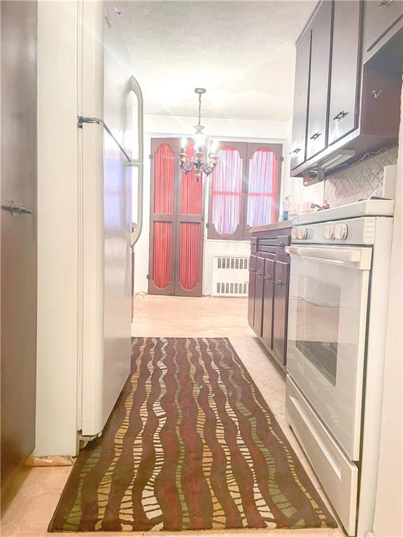 kitchen featuring pendant lighting, a notable chandelier, white appliances, and radiator heating unit