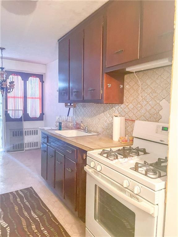 kitchen featuring sink, radiator heating unit, decorative backsplash, and gas range gas stove