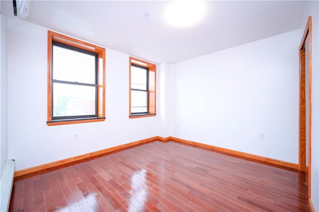 empty room featuring hardwood / wood-style floors and baseboard heating